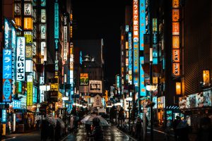 Shinjuku district in tokyo Japan at night. Neon lights and signs light a bustling street.